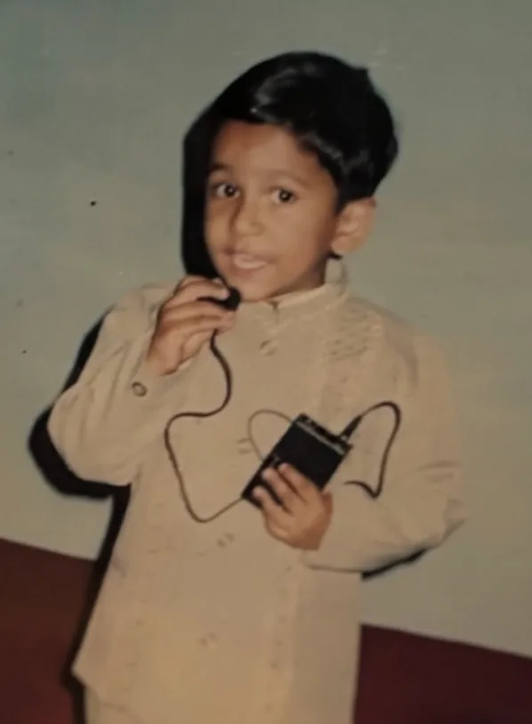 Young Siddharth in a cream outfit holding a microphone.