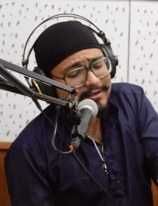 Siddharth wearing headphones and speaking into a studio microphone.