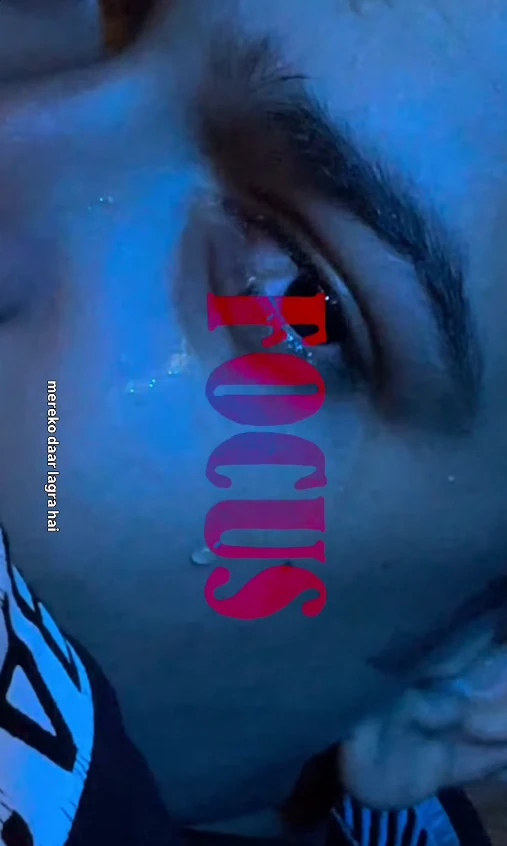 “FOCUS” in tall serif capitals, running vertically in a red-to-magenta gradient over a close-up of an eye with a tear, lit in blue, with a small white caption, “mereko daar lagra hai”, along the left edge.