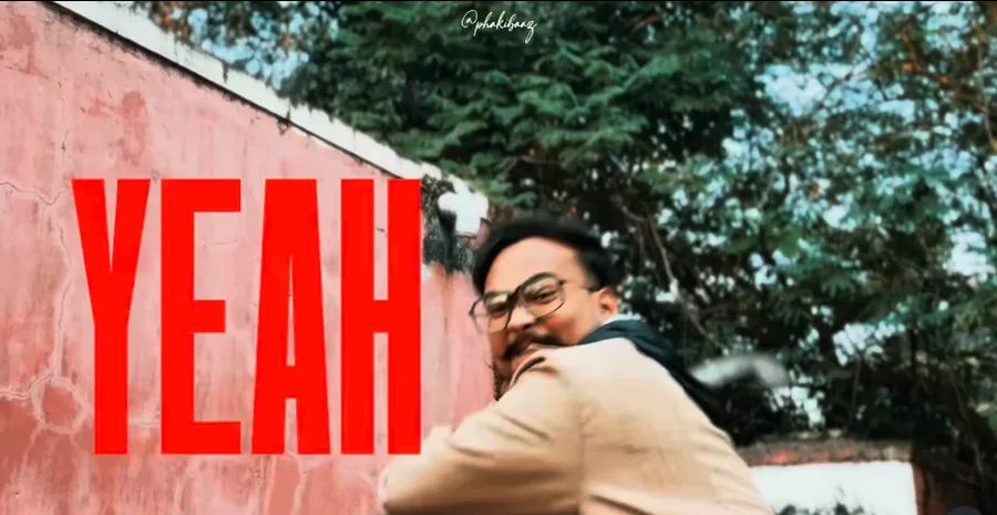 “YEAH” in tall, condensed red capitals on a weathered pink wall, with me turning toward the camera at the lower right.